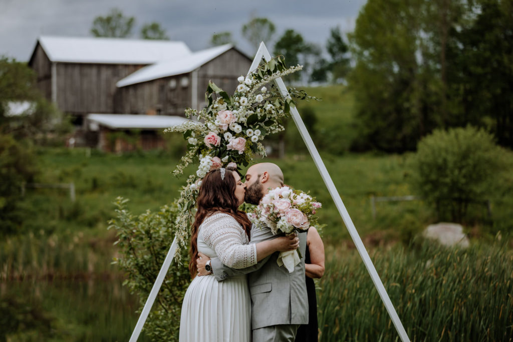 Man and woman having their first kiss at end of wedding ceremony at Fox Hill Farm