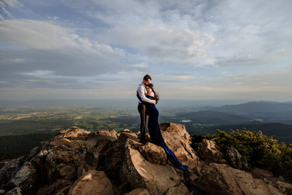 Man and woman holding each other on mountain during sunrise