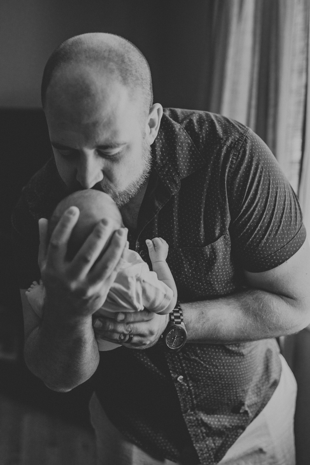 Dad kissing newborn baby on forehead