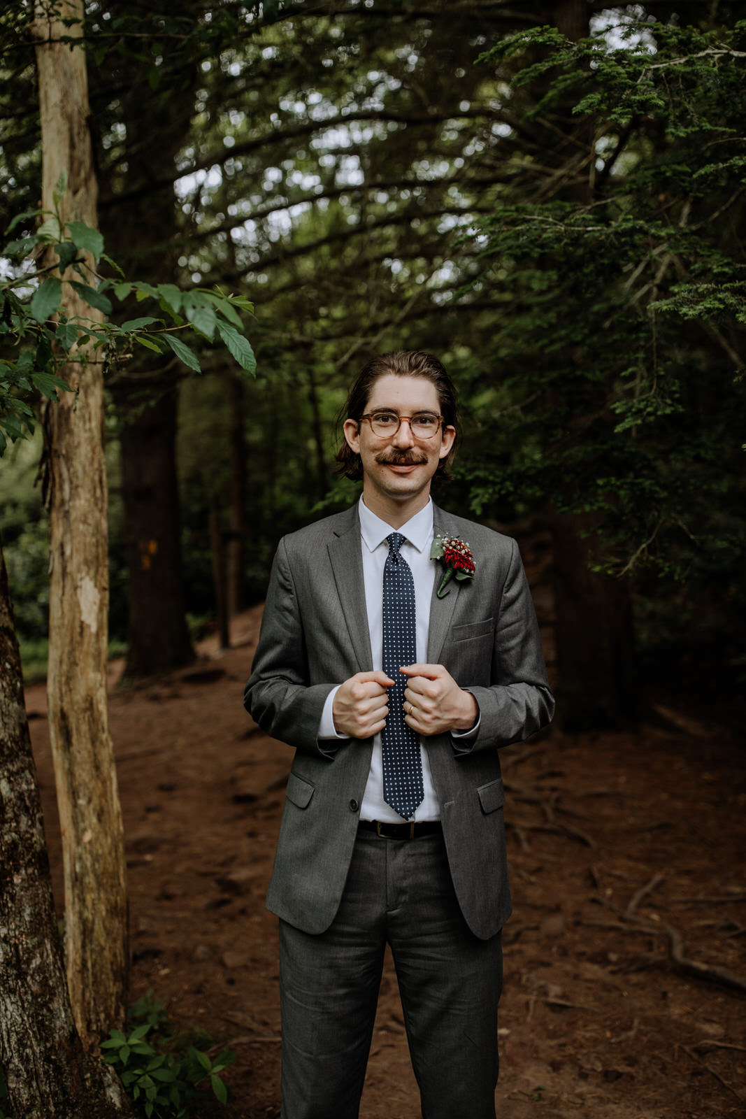 Portrait of a groom in the woods holding his suit jacket