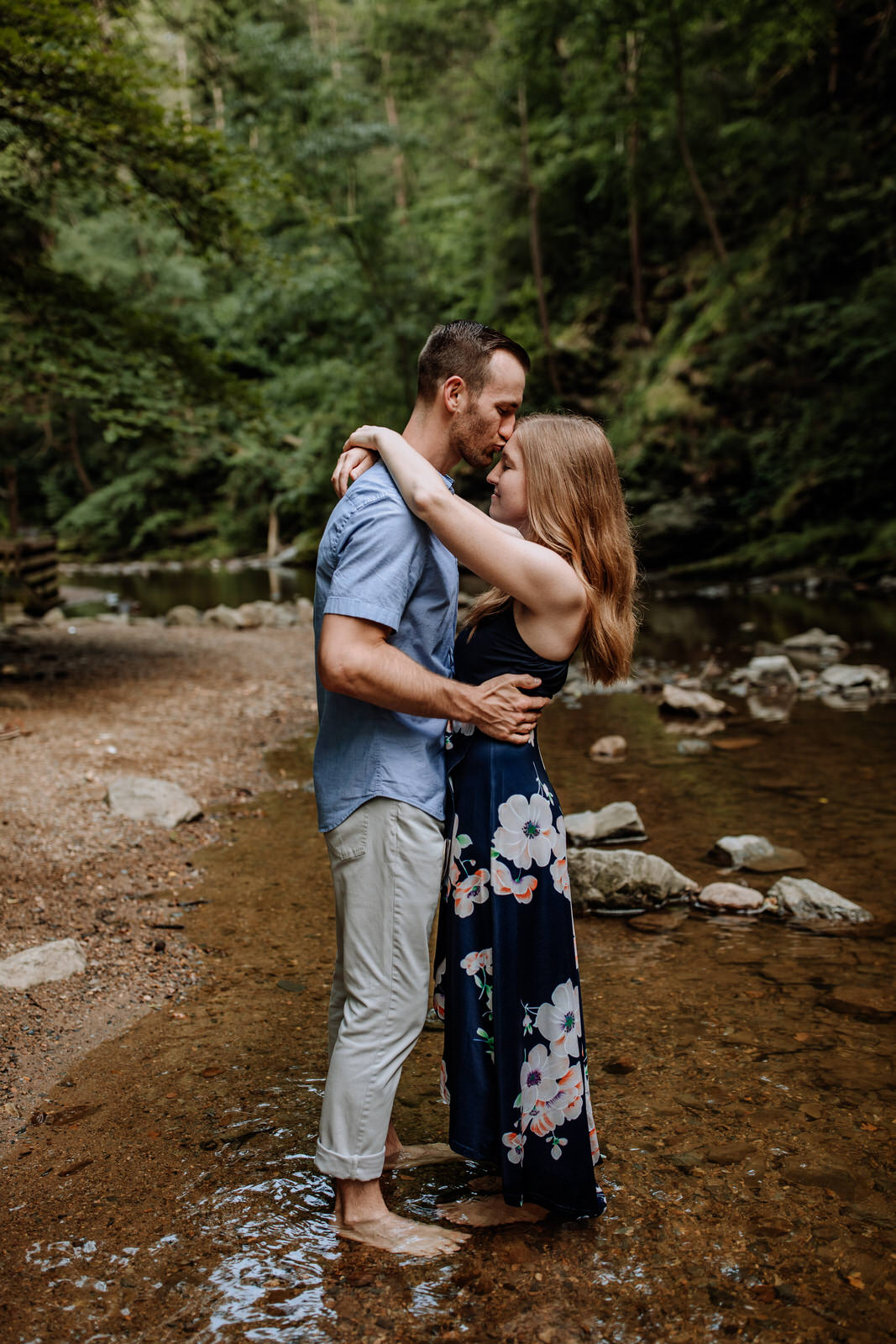 Man kissing woman on forehead while standing in a stream