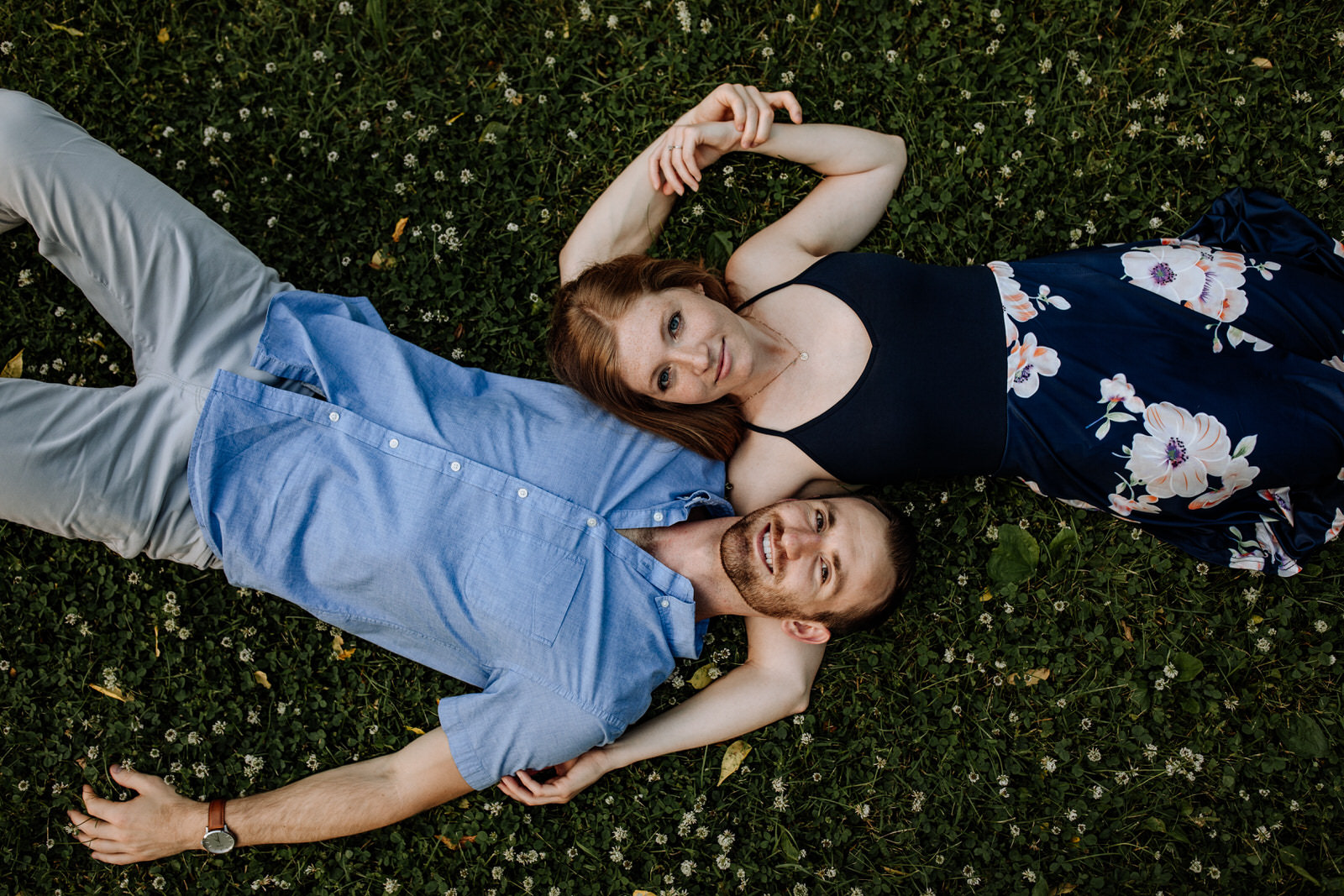 Woman and man lying on the grass looking up at the camera