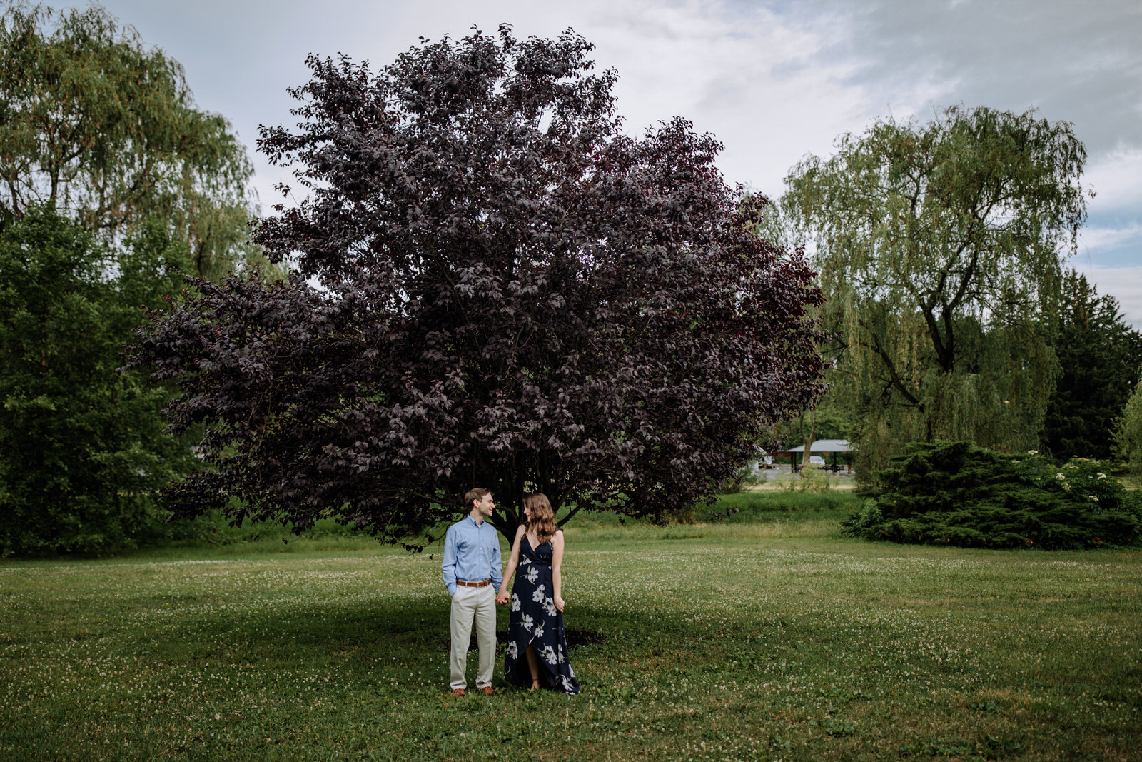 Man and woman standing next to each other under a purple leaved tree