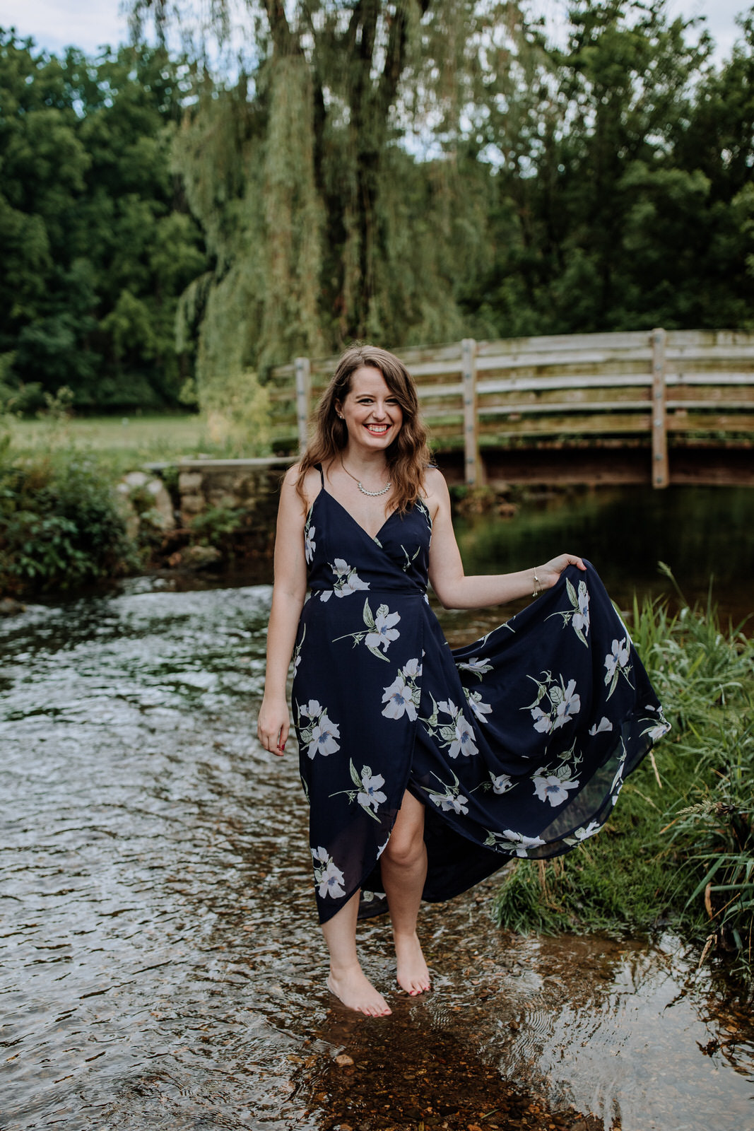 Woman standing in a low stream while holding her dress to the side