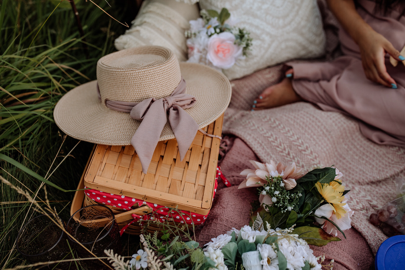 Close up of a hat, picnic basket, blankets, flower bouquet