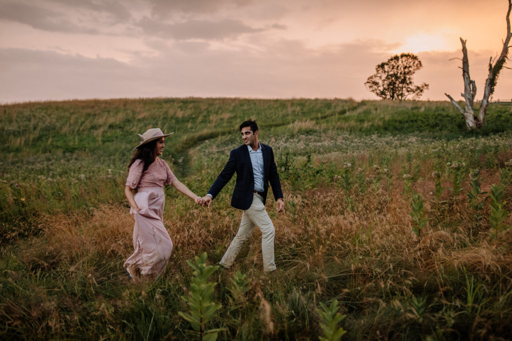 Man and woman walking through a field at sunset