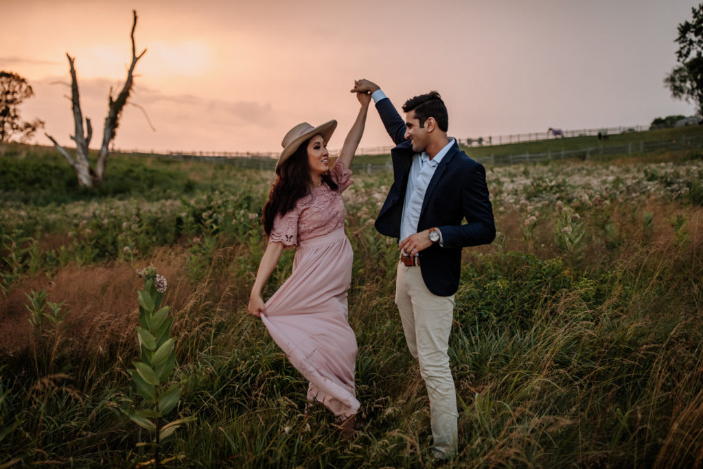 Woman and man dancing in a field at sunset