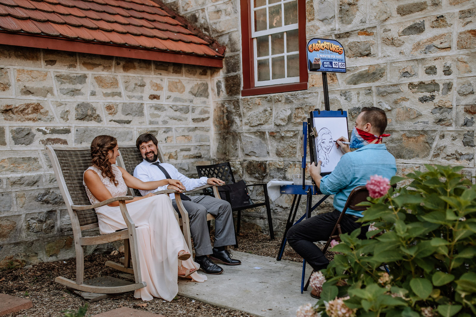 Wedding guests sitting and having their caricature drawn by an artist