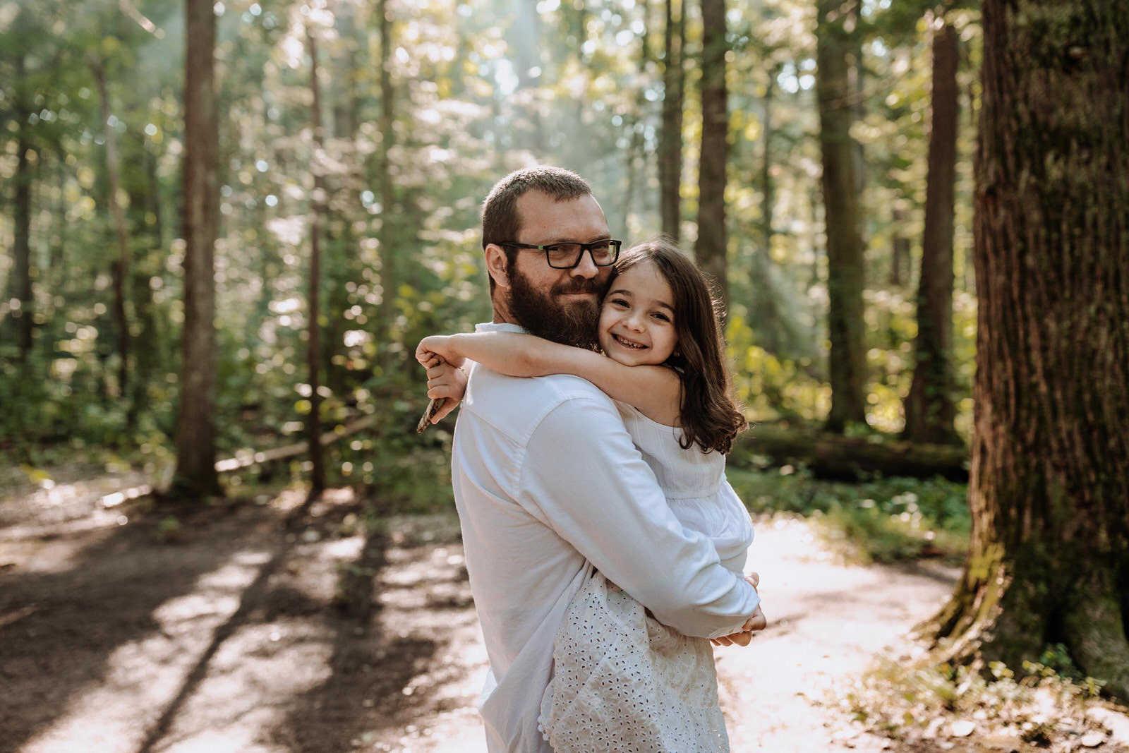 Bearded man holding his daughter and both smiling looking at the camera