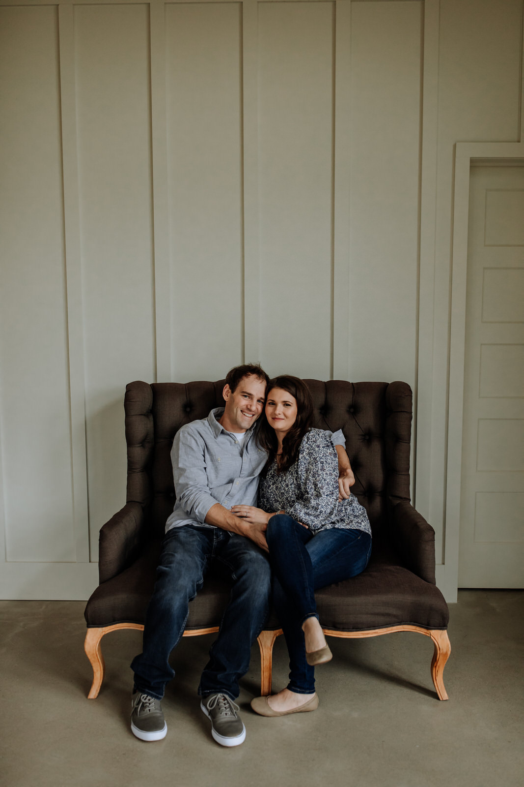 Engagement photo of a couple sitting on a couch inside The Farm Bakery and Events