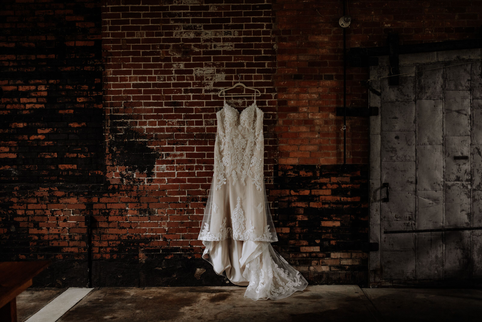 Wedding dress hanging on an industrial brick wall