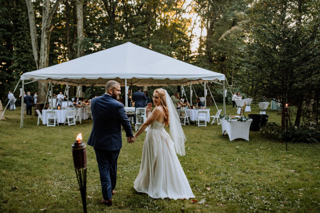 Man and woman walking towards a tented reception in their backyard