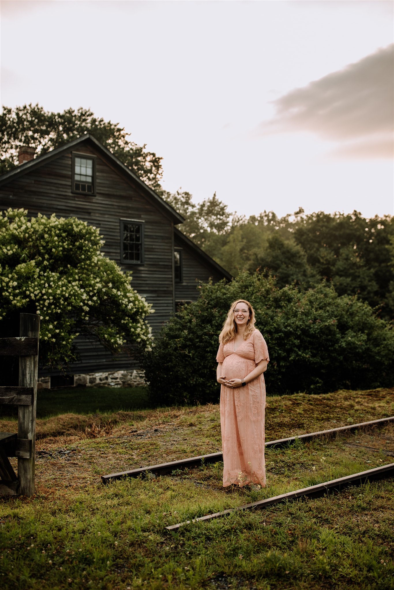 Pregnant woman in pink dress standing on movie set railroad tracks at Eckley Miners Village