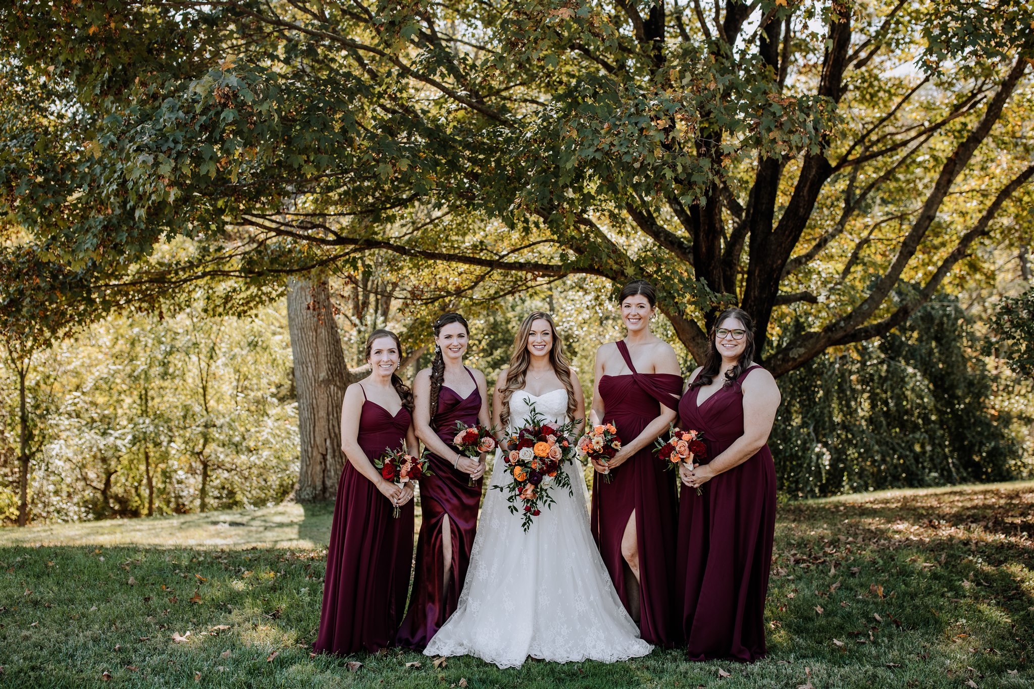 Bride and bridal party girls in dresses in front of trees